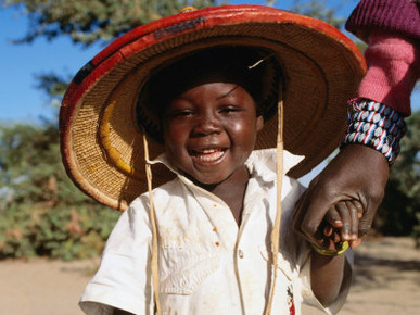 Young Smiling Boy Wearing a Typical Mali Hat and Holding His Mother's Hand, Djenne, Mopti, Mali